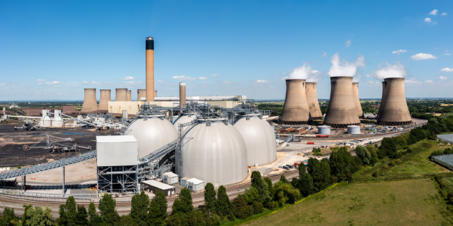 An aerial view of a large power plant that burns biofuel instead of coal, with storage tanks visible in the landscape. 