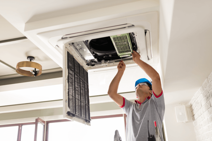 Electrician installing air conditioning system in an office interior