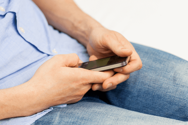 A close-up shot of a man using a smartphone inside his home